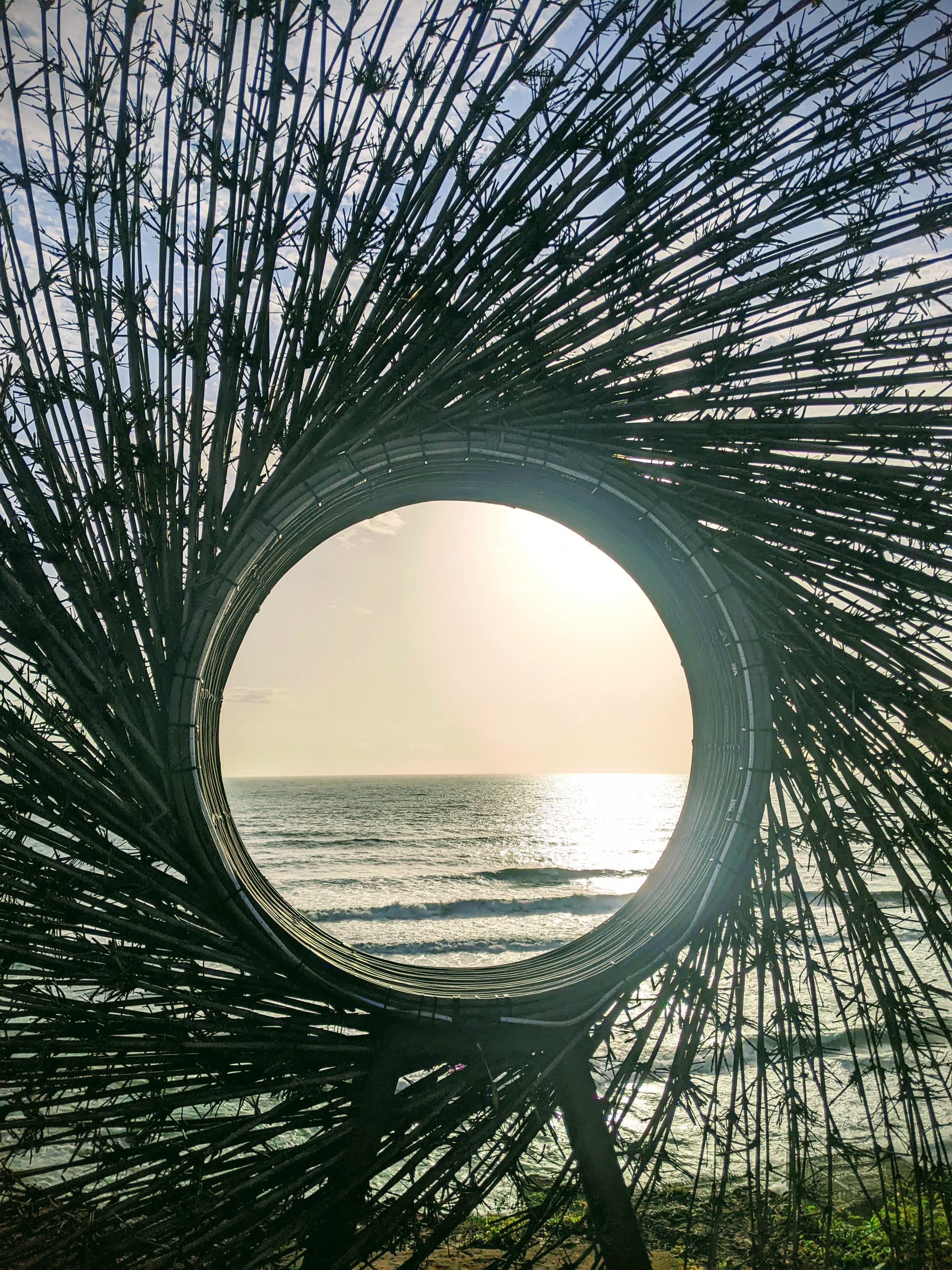 The sea viewed through a circular bamboo sculpture on a beach