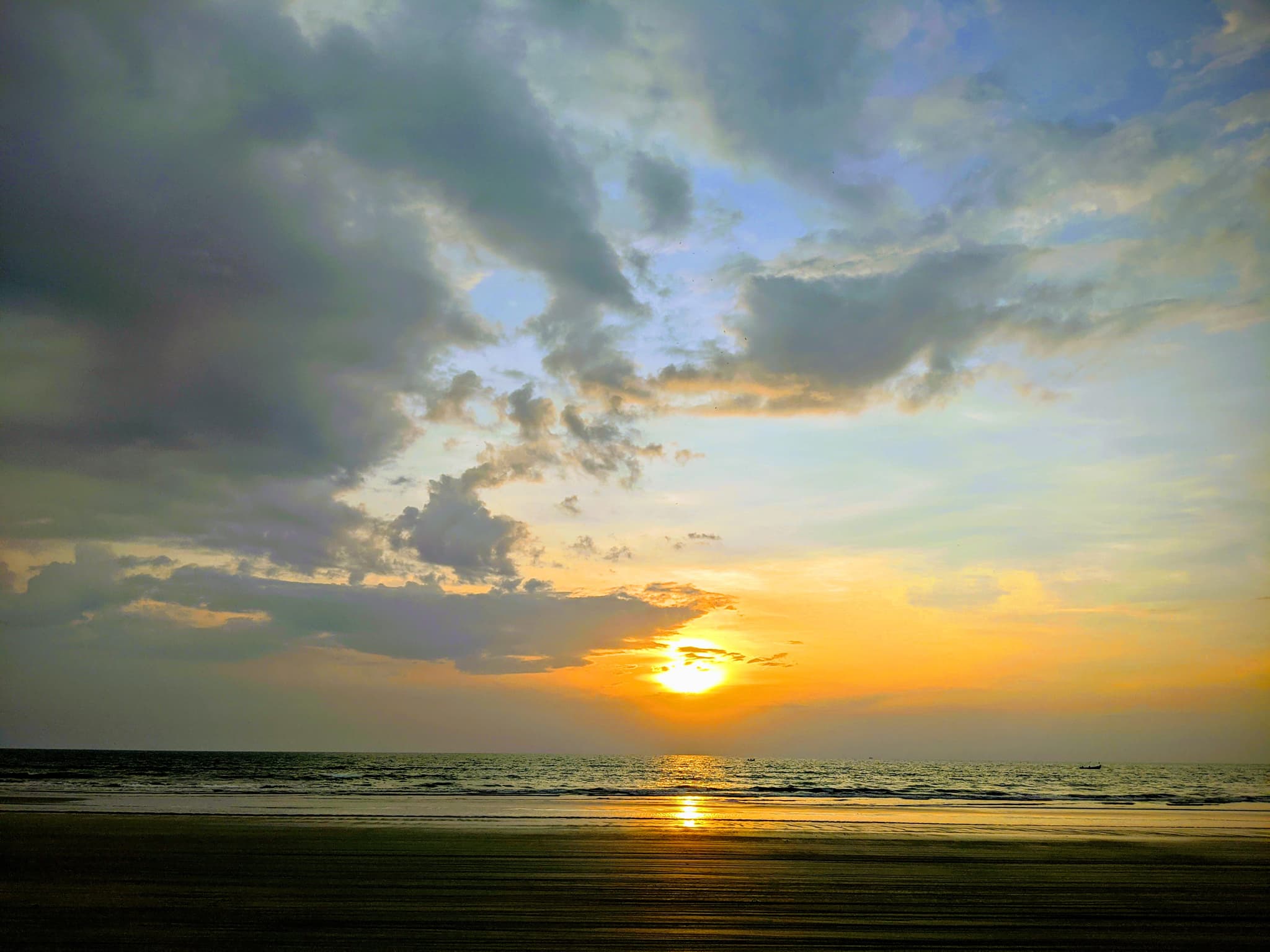 A dramatic beach sunset with towering clouds in gold and blue