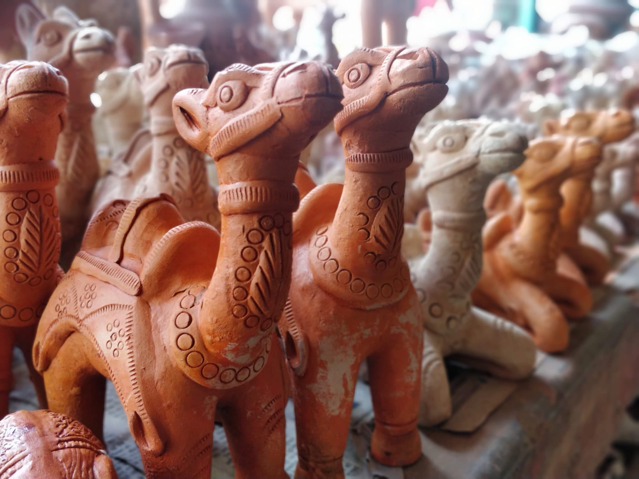 Row of terracotta clay camel figurines with ornate designs