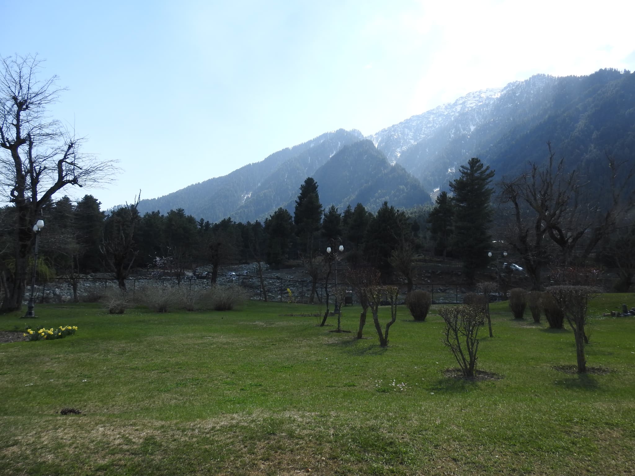 Mughal garden with snow-capped mountains behind, bare trees, green lawns
