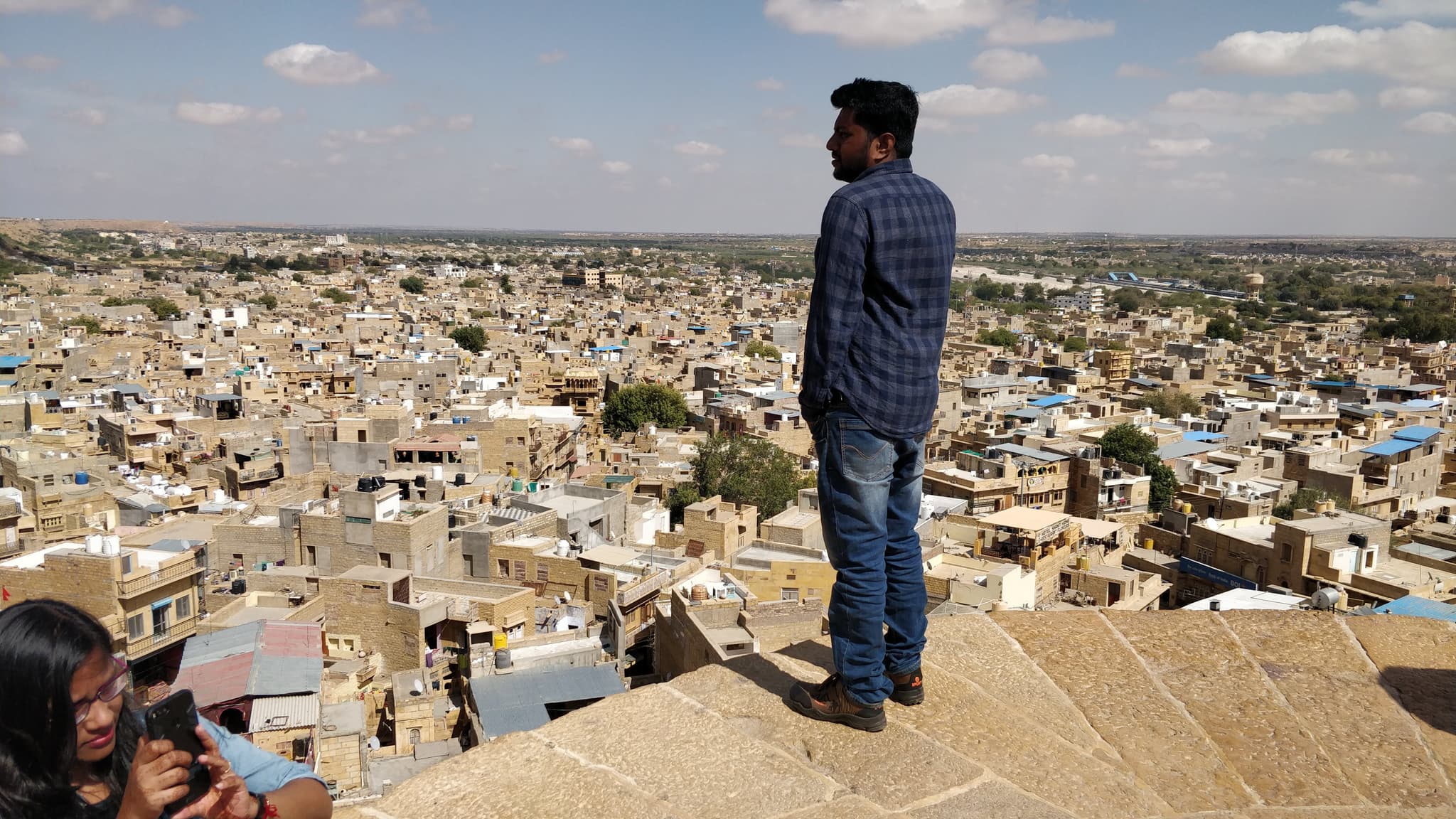 A lone figure standing on Jaisalmer Fort, overlooking the golden city below