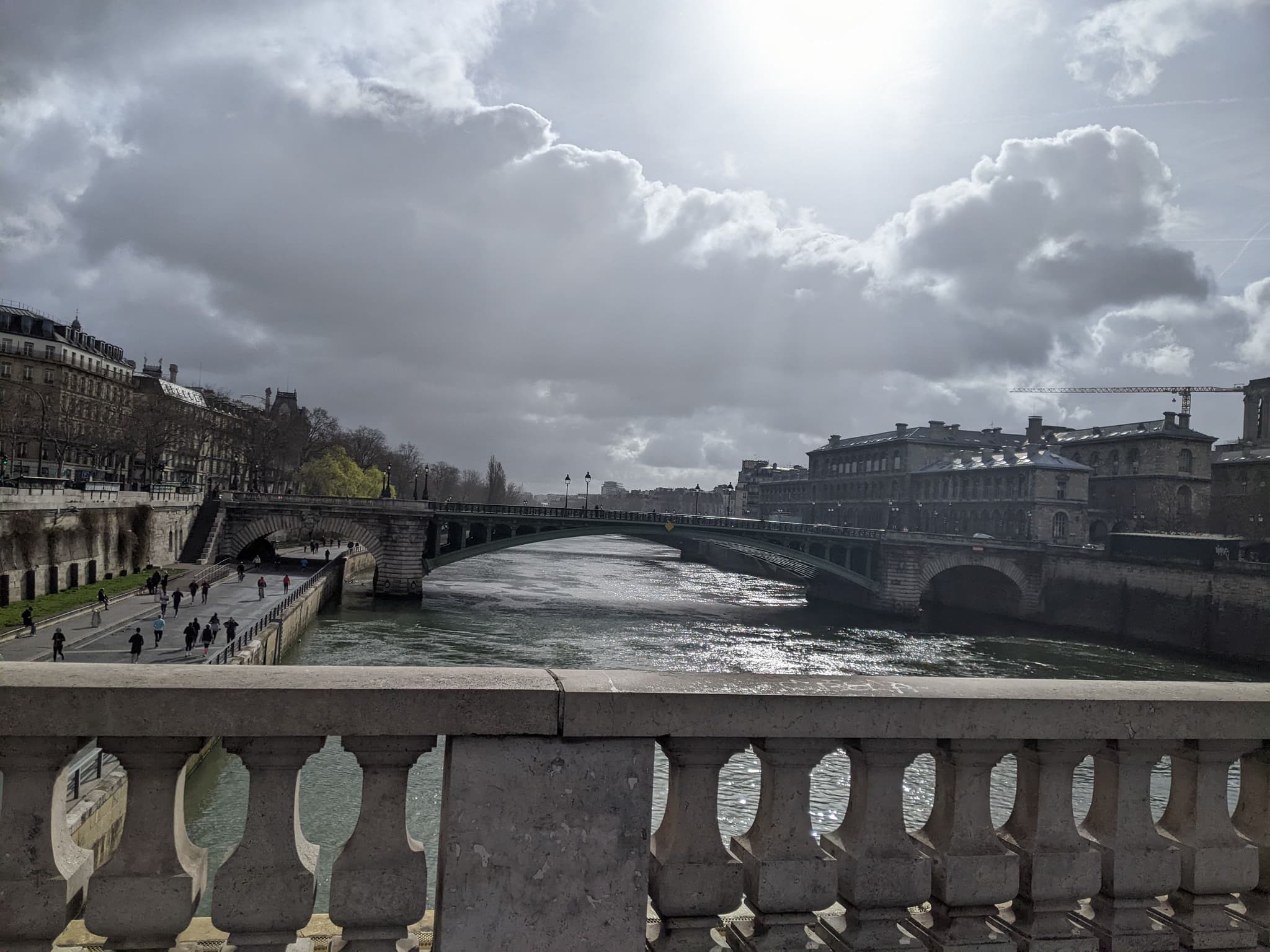 Seine River in Paris from bridge, dramatic clouds with sun breaking through