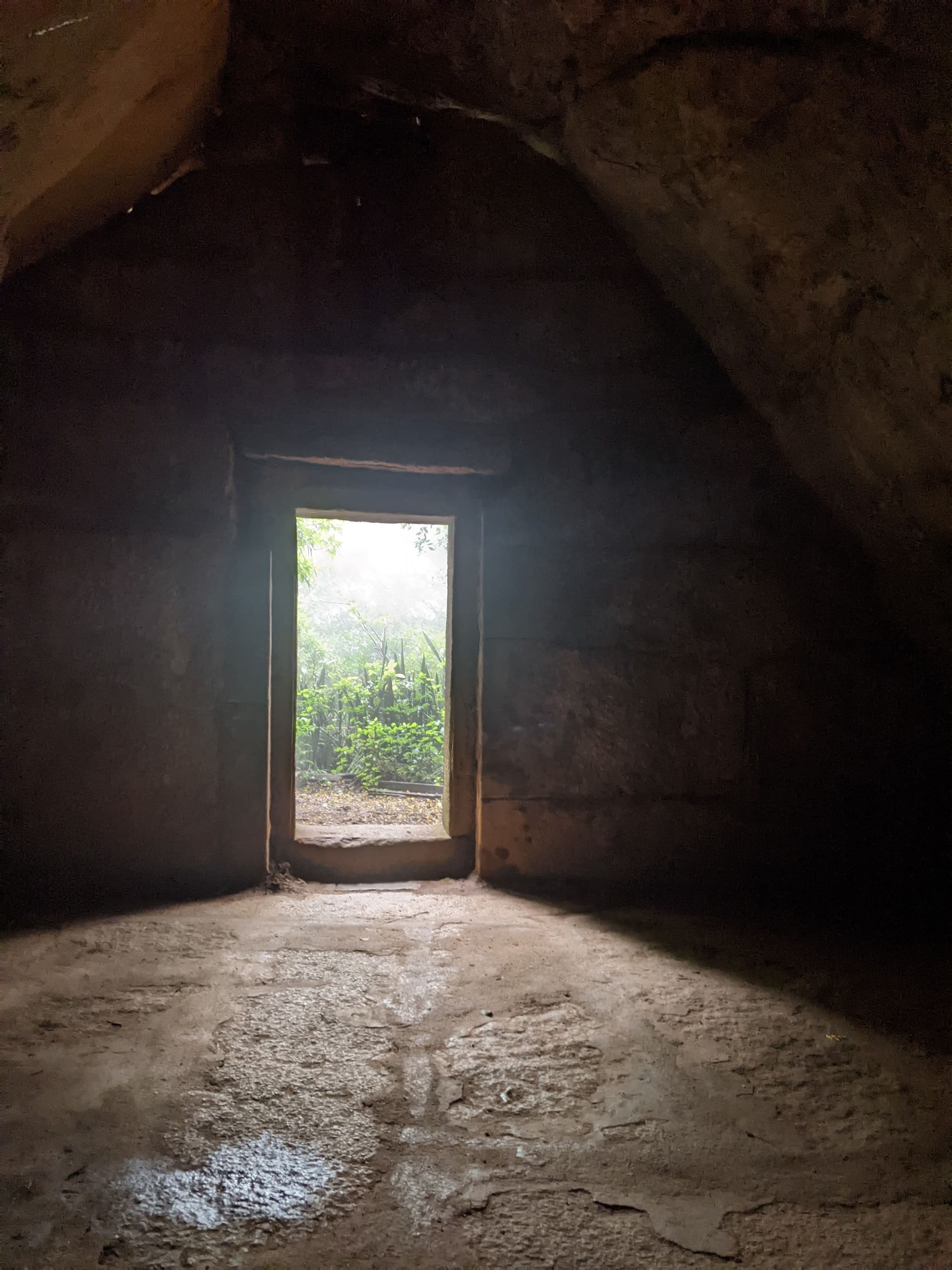 Light streaming through doorway of ancient stone cave into dark interior