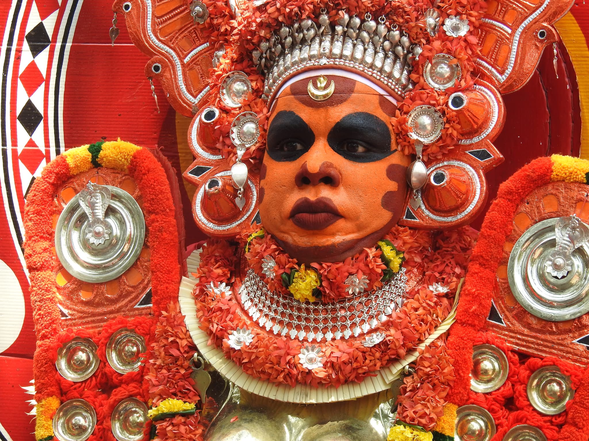 Close-up of a Theyyam performer in full ceremonial face paint and ornate headdress