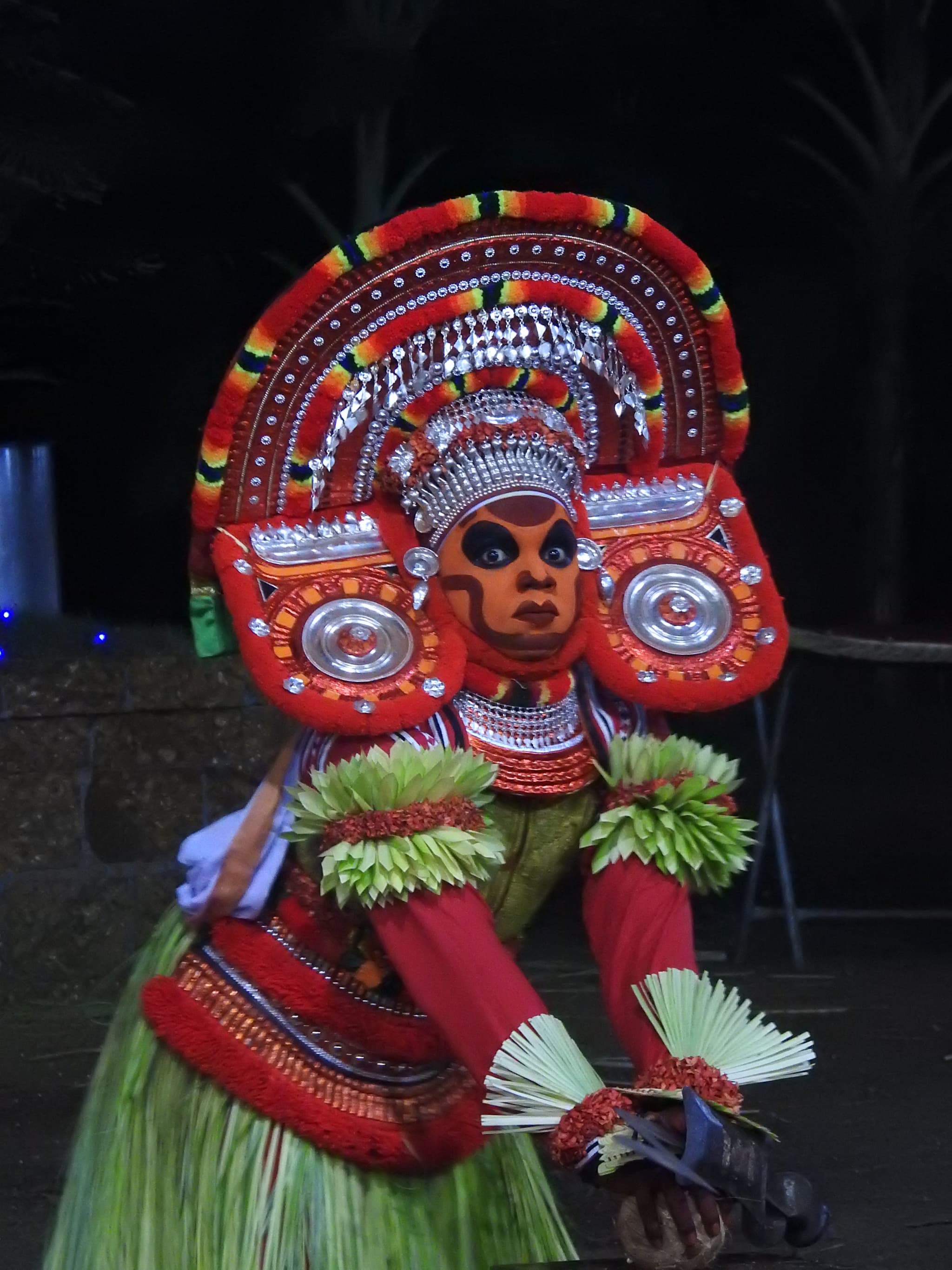 Theyyam performer in full elaborate red-orange costume and face paint