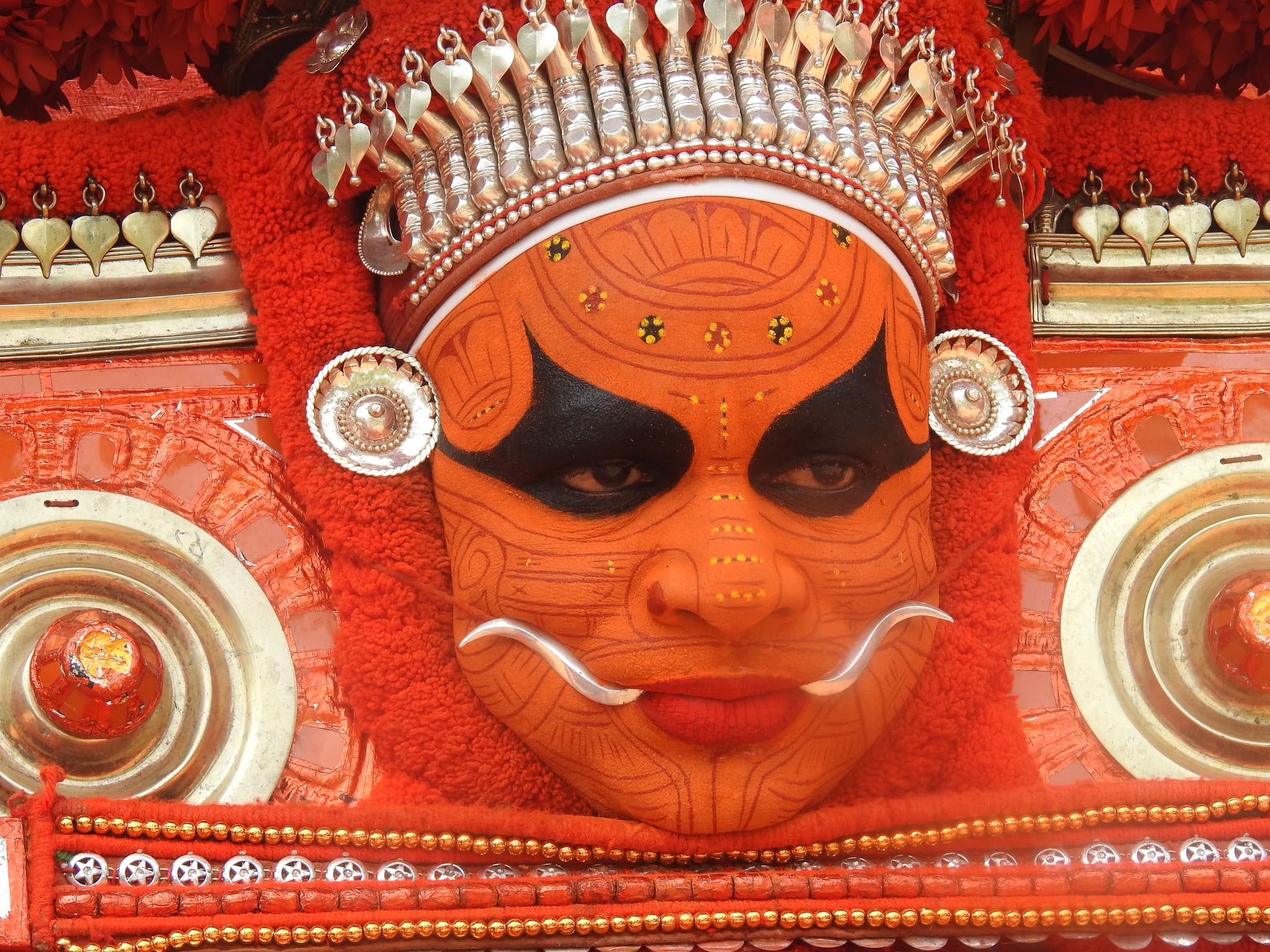 A Theyyam performer in full ceremonial regalia during a night ritual